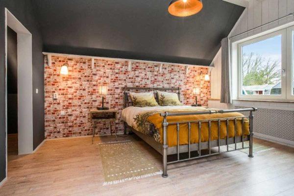 een slaapkamer met een bed en een bakstenen muur bij Ontbijt bij De Boerenmeid in Hoogwoud