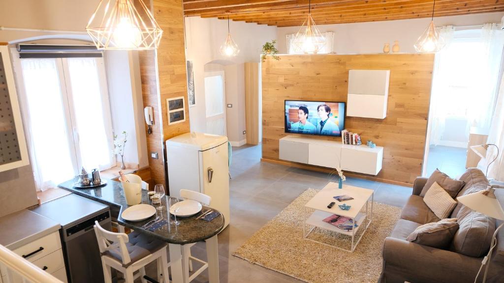 Antiche Rive Holidays Apartments في سالو: مطبخ وغرفة معيشة مع أريكة وتلفزيون