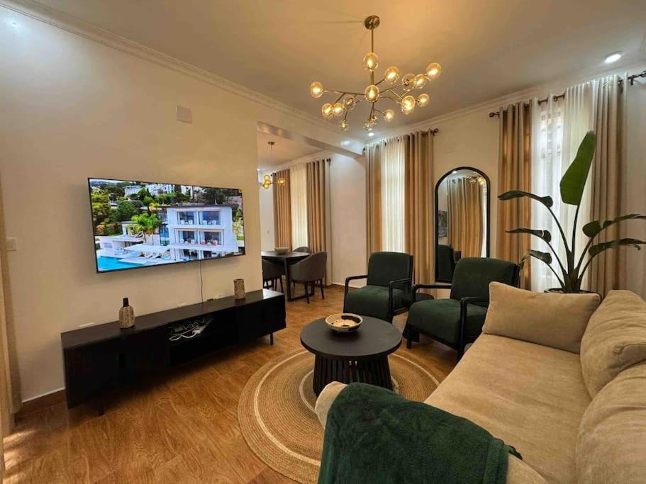 een woonkamer met een bank en een flatscreen-tv bij Nzuri Nest -Queen in Kigali