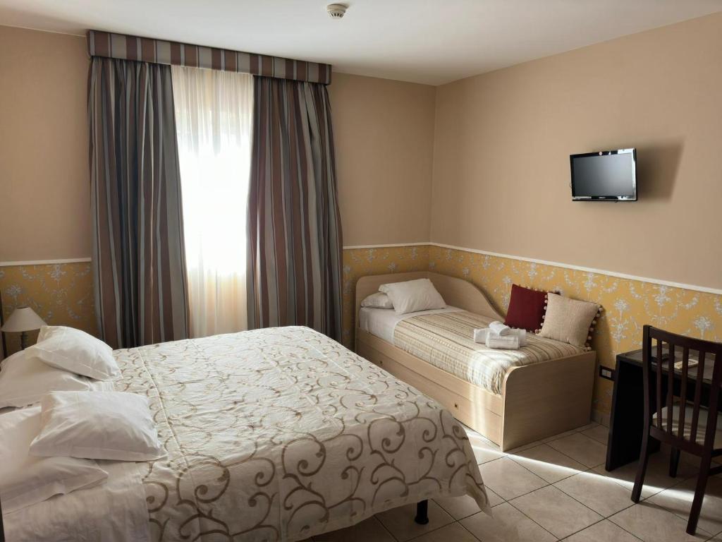 a hotel room with two beds and a window at Hotel De La Ville Relais in Fiumicino