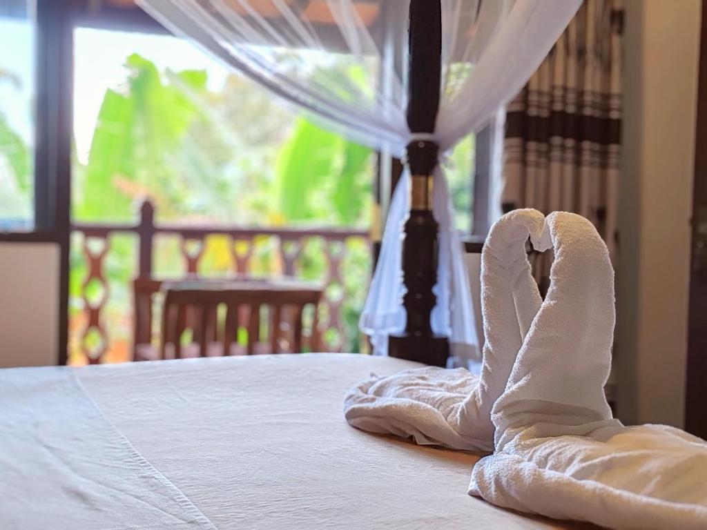 a pair of feet in white towels on a bed at The Jungle View in Mirissa