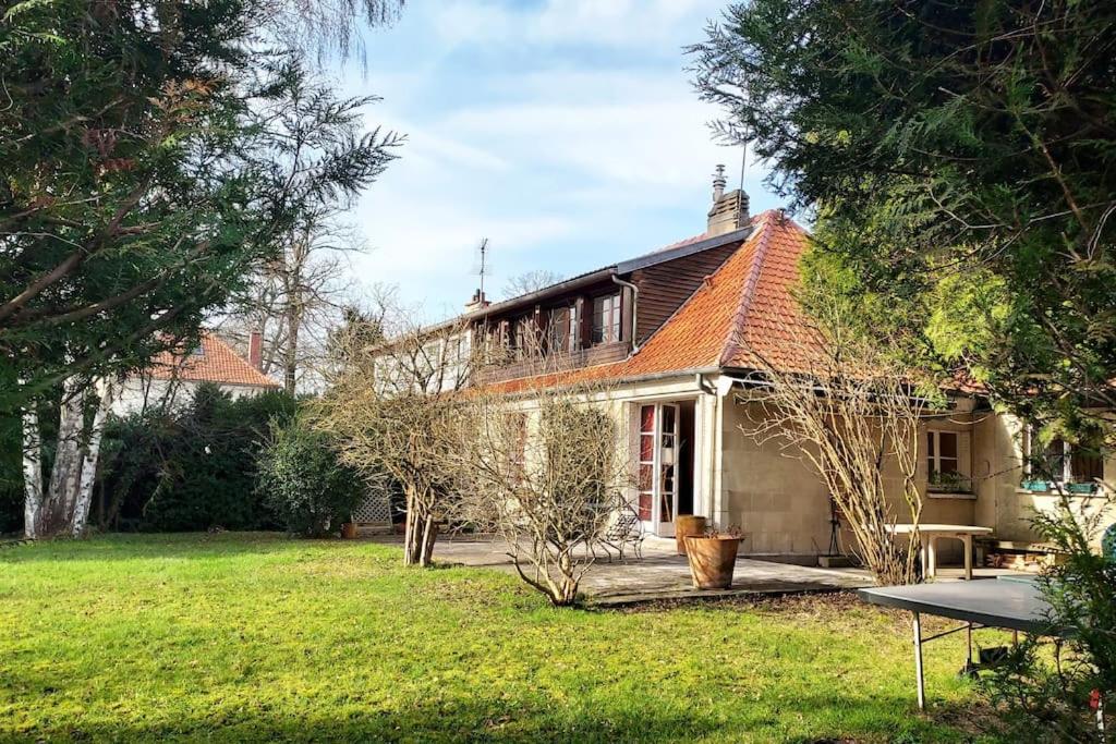 una casa con un patio con una mesa delante en Maison dans parc privé (JO 2024), en La Celle-Saint-Cloud