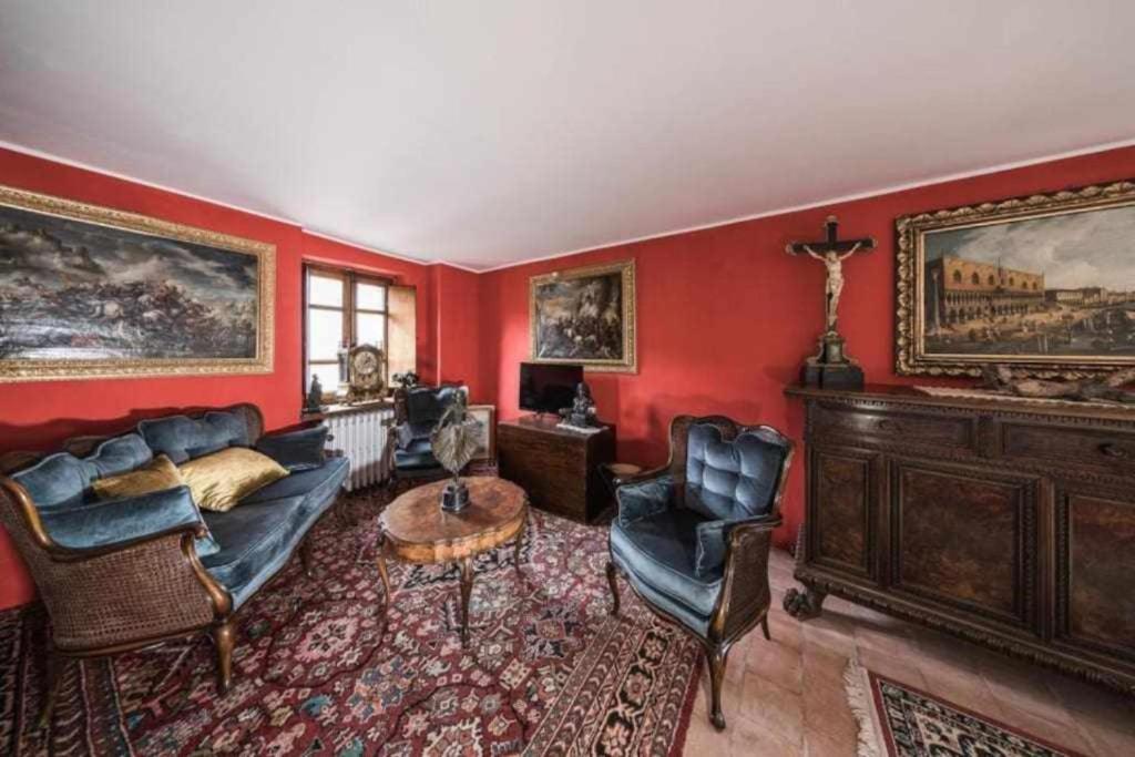 a living room with red walls and a couch and chairs at Torre del 1300 Un atto damore in Castiglione