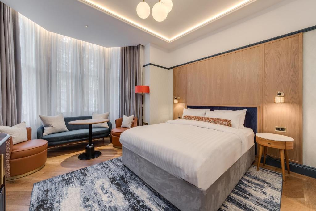 Cette chambre comprend un grand lit et un canapé. dans l'établissement Mornington Hotel London Kensington, BW Premier Collection, à Londres