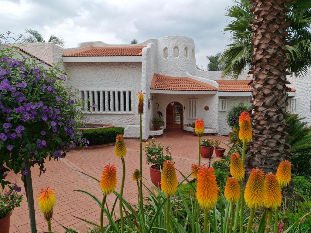 a white house with flowers in front of it at Villa Sardinia Guest House in Midrand