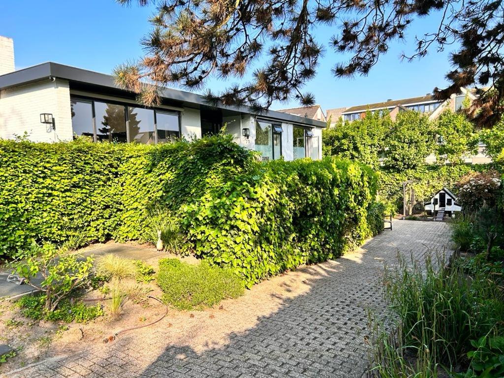 a house with a hedge in front of a building at Villa Park in Bennebroek