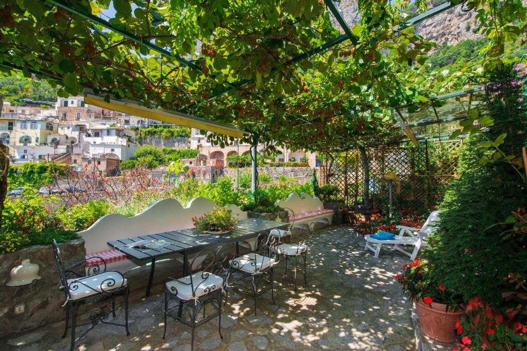 einen Garten mit einem Tisch und Stühlen unter einer Pergola in der Unterkunft YourHome - Maison Iolanda Positano in Positano
