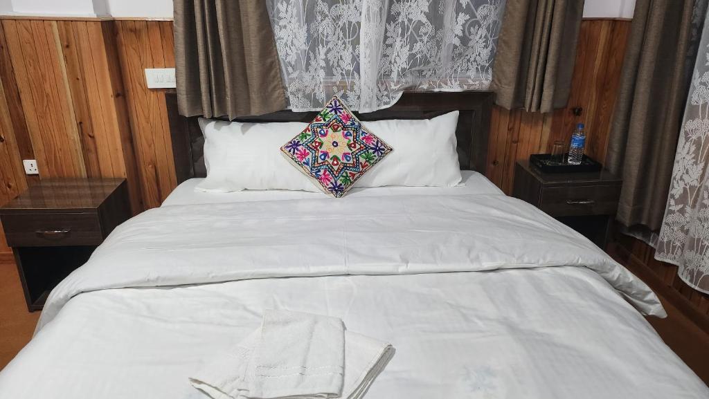 a white bed with a pillow on top of it at Yalung Homestay in Darjeeling