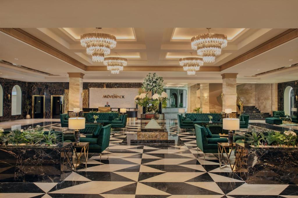 a lobby with green furniture and chandeliers at Mövenpick Hotel Cairo - Media City in 6th Of October