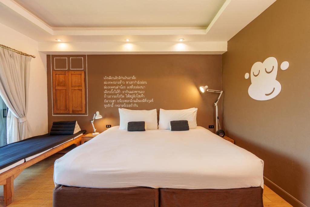 a bedroom with a large white bed with a monkey on the wall at Blu Monkey Brown House Udonthani in Udon Thani