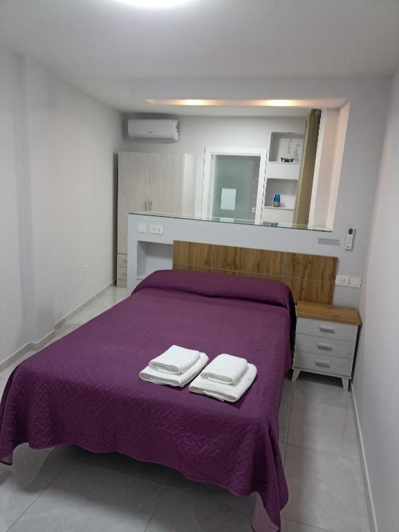 sypialnia z fioletowym łóżkiem z 2 ręcznikami w obiekcie oasis en Tenerife 3 w mieście El Escobonal