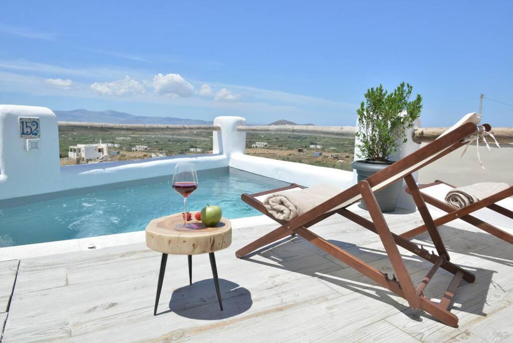 a glass of wine on a table next to a pool at Villa Areti Naxos in Glinado Naxos