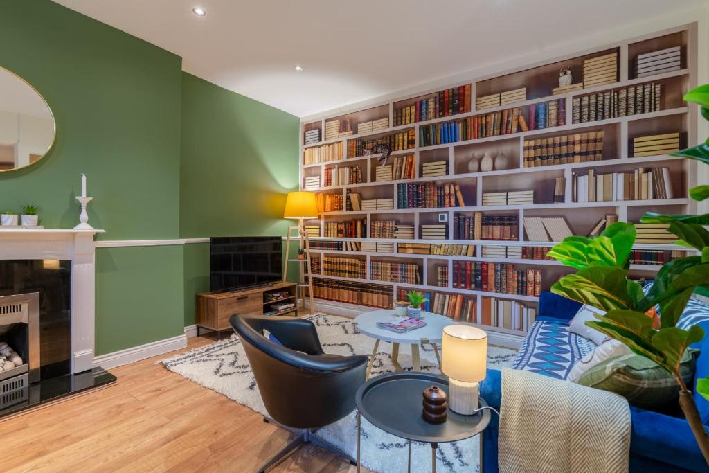 una sala de estar con paredes verdes y una gran estantería. en Regency Basement Apartment en Cheltenham