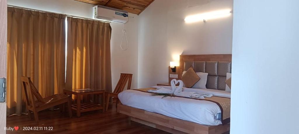 Jim Corbett Tiger Resort في Belparāo: غرفة نوم بسرير ومكتب ونافذة