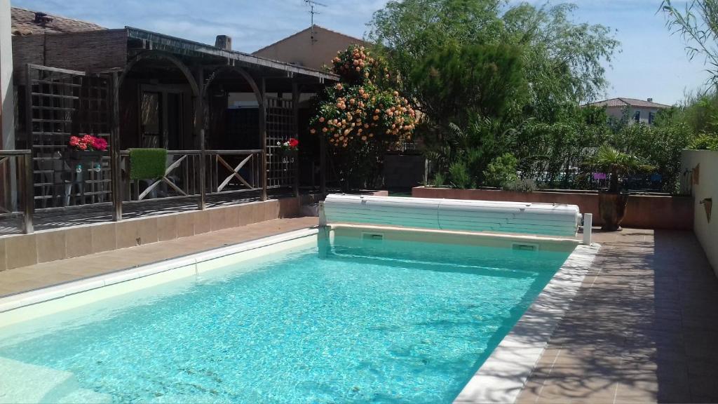 - une piscine avec banc devant un bâtiment dans l'établissement Aux Portes de la Camargue, à Arles
