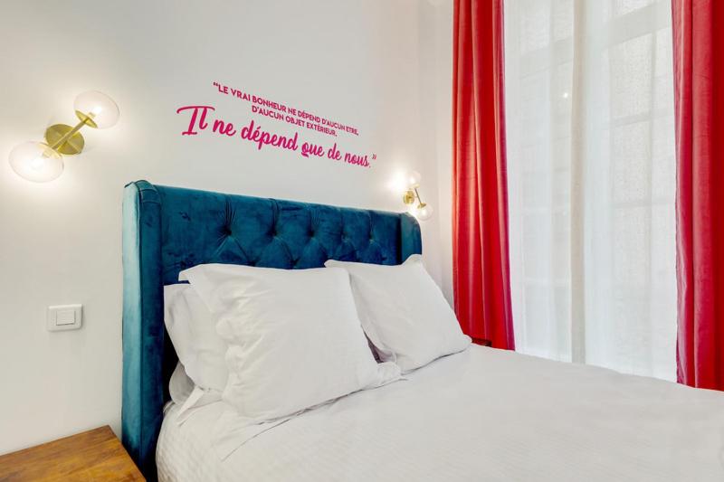 Una cama con un cabecero azul con un cartel. en 206 Suite Hermès - Superb apartment in Paris, en París