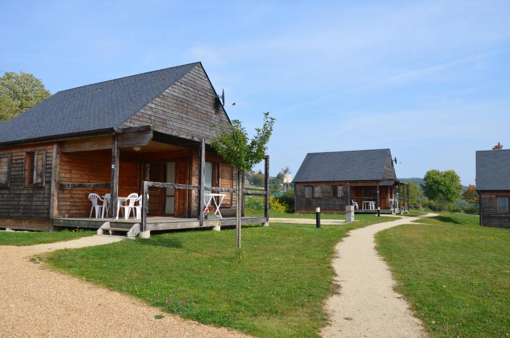 eine Blockhütte mit einer Veranda und Stühlen auf dem Rasen in der Unterkunft Les lodges de Sainte-Suzanne in Sainte-Suzanne