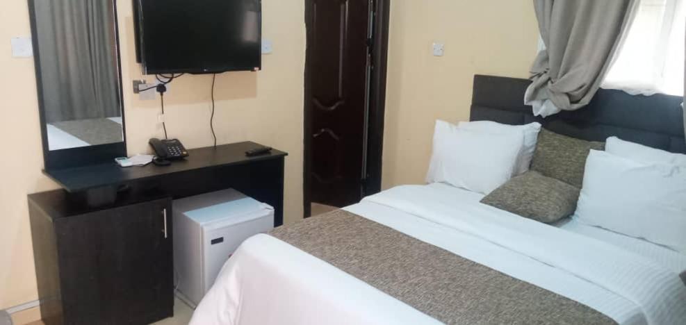una camera d'albergo con letto e TV di Benji Apartments a Jiru