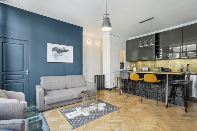 uma sala de estar com um sofá e uma cozinha em 142 Suite Ober - Superbe Appartement à Paris em Paris