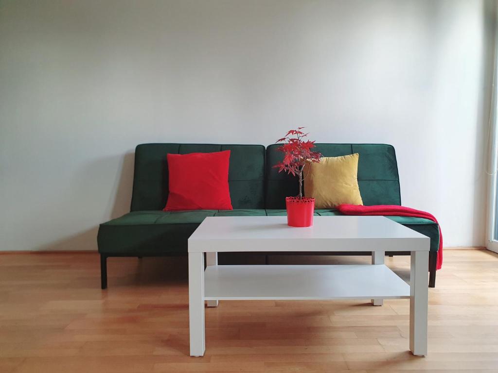 a green couch with red and yellow pillows and a table at Near Lake One Bedroom Adorable Apartment in Vienna