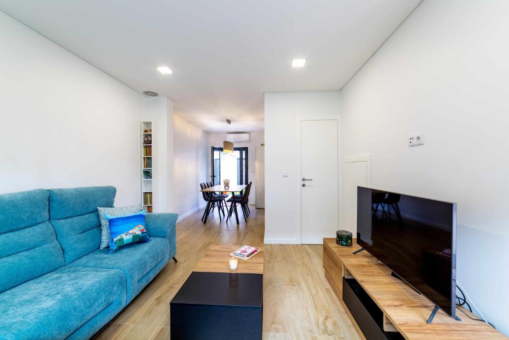 Una sala de estar con un sofá azul y un televisor de pantalla plana. en MY HOME IS YOUR HOME Viana House, en Viana do Castelo