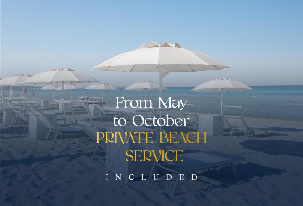 a beach with tables and umbrellas on the sand at Grand Hotel Costa Brada in Gallipoli