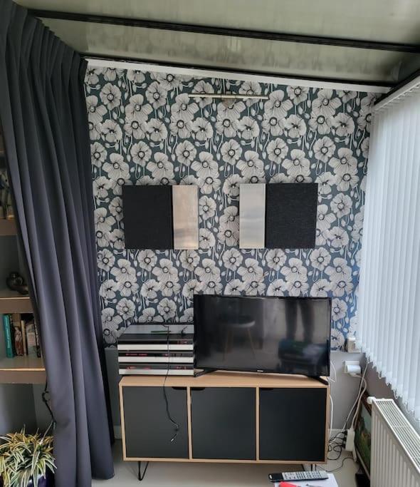 a tv sitting on top of a stand in front of a wall at Appartement de charme et jardin in Bihorel