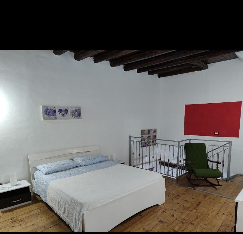 ein weißes Schlafzimmer mit einem Bett und einem grünen Stuhl in der Unterkunft A' casuzza in Palermo
