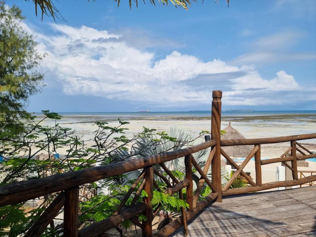 a wooden boardwalk leading to a beach with the ocean at Kwa Mama Village Beach Resort in Dar es Salaam
