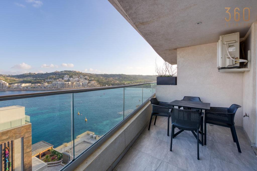 a balcony with a table and chairs and a view of the ocean at Waterfront 3BR home, with private balcony by 360 Estates in St. Paul's Bay