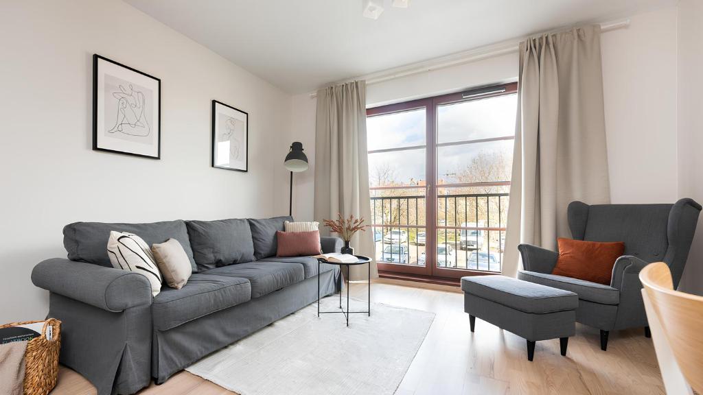 a living room with a gray couch and two chairs at Flatbook - City Center SPA Apartments A,B,C in Gdańsk