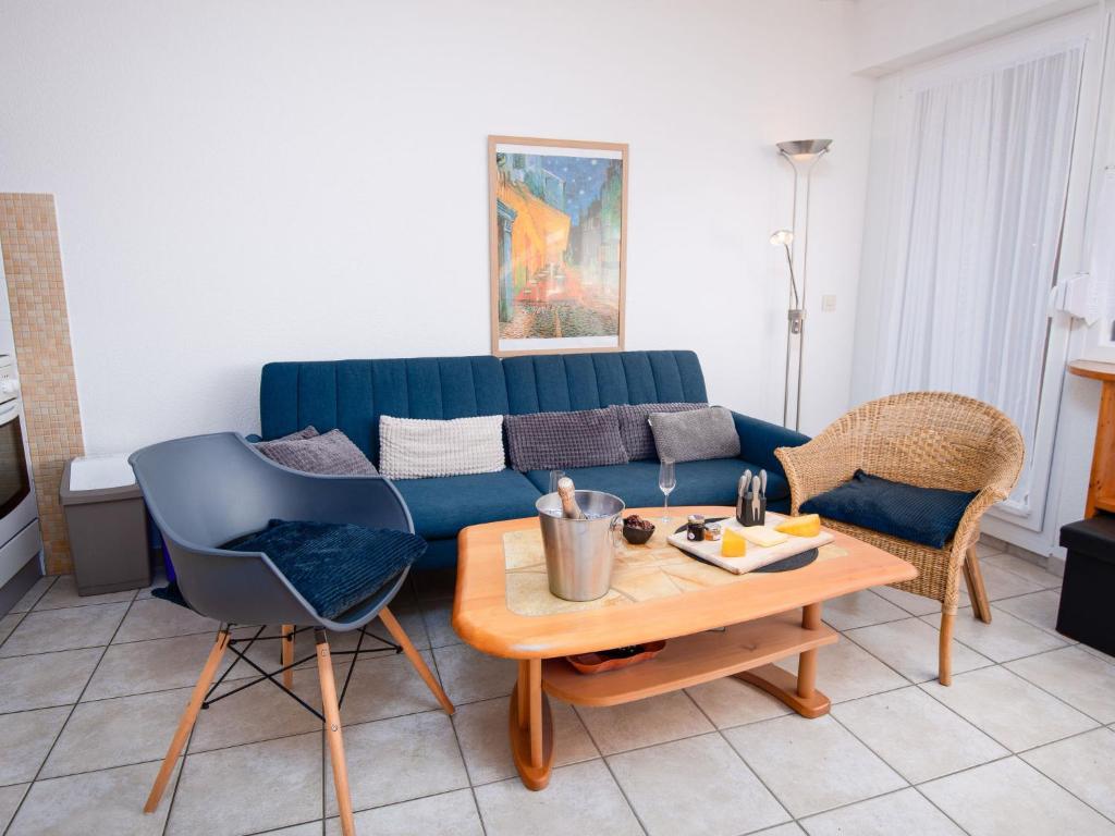 ein Wohnzimmer mit einem blauen Sofa und einem Tisch in der Unterkunft Apartment Achtern Diek by Interhome in Norddeich