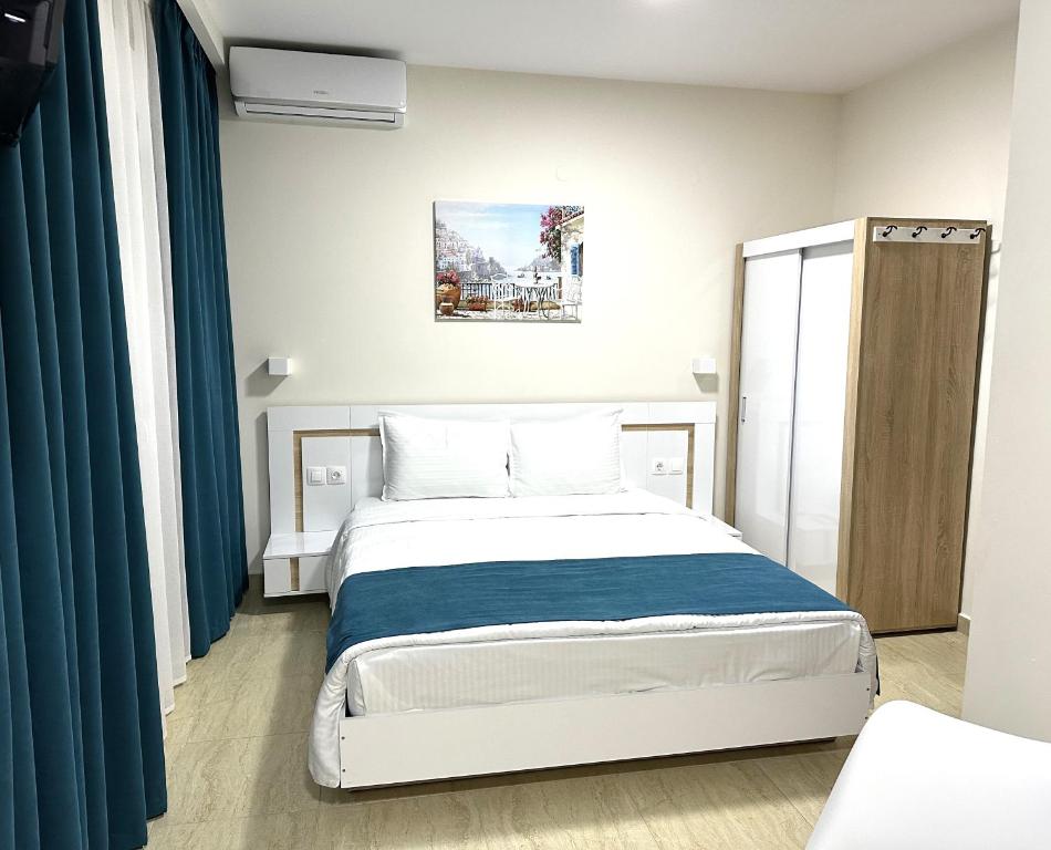 sypialnia z dużym łóżkiem z niebieskimi zasłonami w obiekcie Navarino Luxe Suites with Sea View w mieście Perea