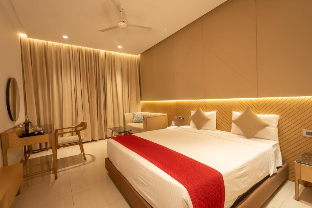 a hotel room with a large bed and a desk at Hotel Parsons Court in Dindigul