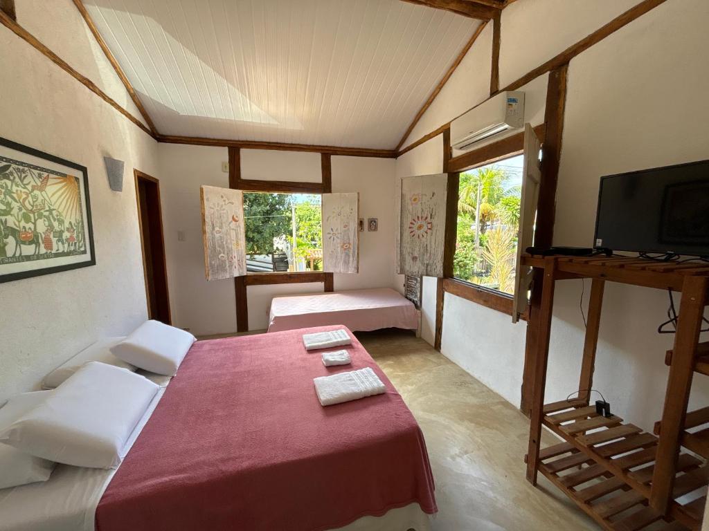 a room with two beds and a tv in it at Vila Cizinho in Itaúnas