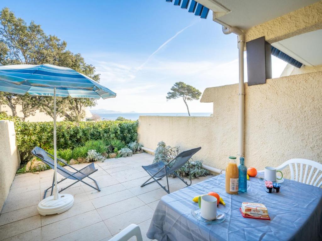 een blauwe tafel met stoelen en een parasol op een patio bij Studio Les Louvans-3 by Interhome in Saint-Aygulf