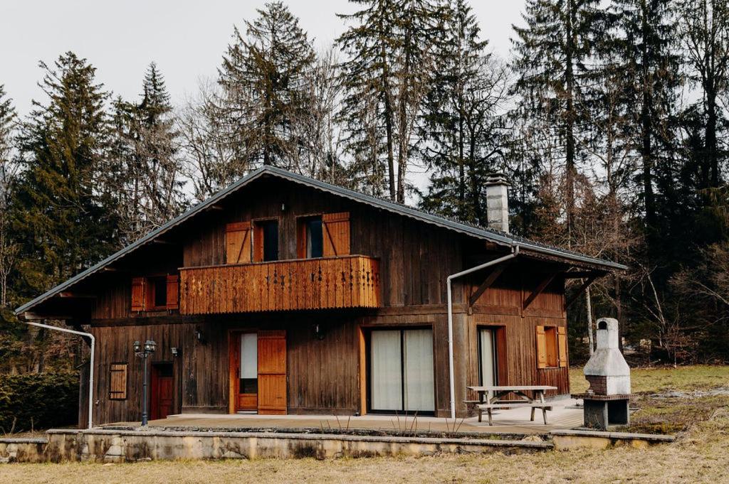 a large wooden house with a bench in front of it at Chalet des bois de Criou in Morillon