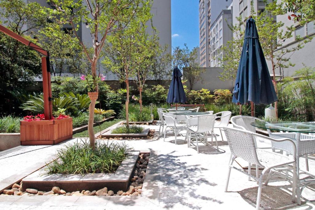 een patio met tafels, stoelen en parasols bij George V - Itaim in Sao Paulo