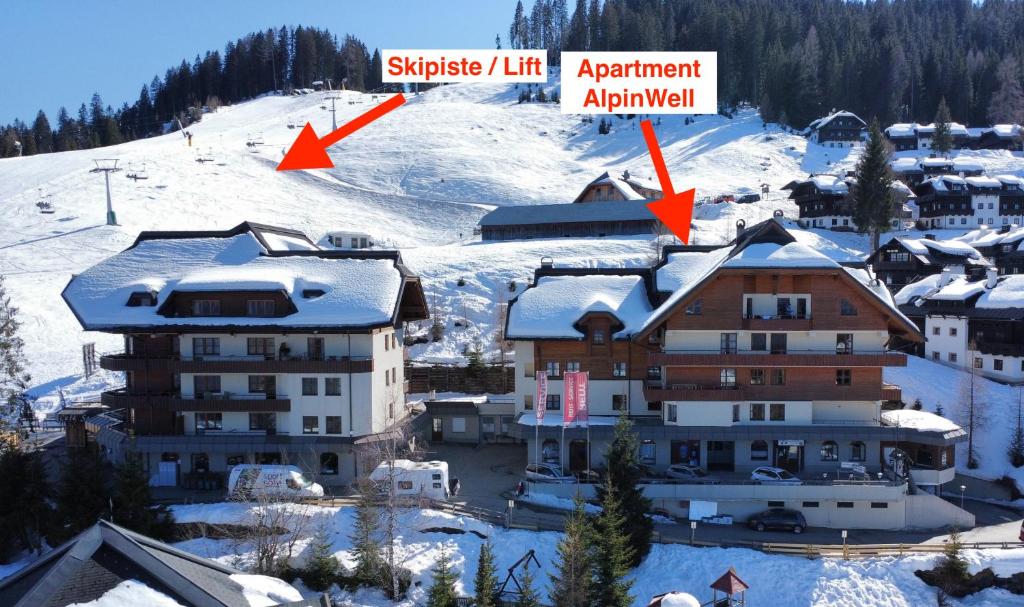a view of a hotel in the snow with two arrows at Sonnleitn AlpinWell Appartment (Ski in&out + Wellness) in Hermagor