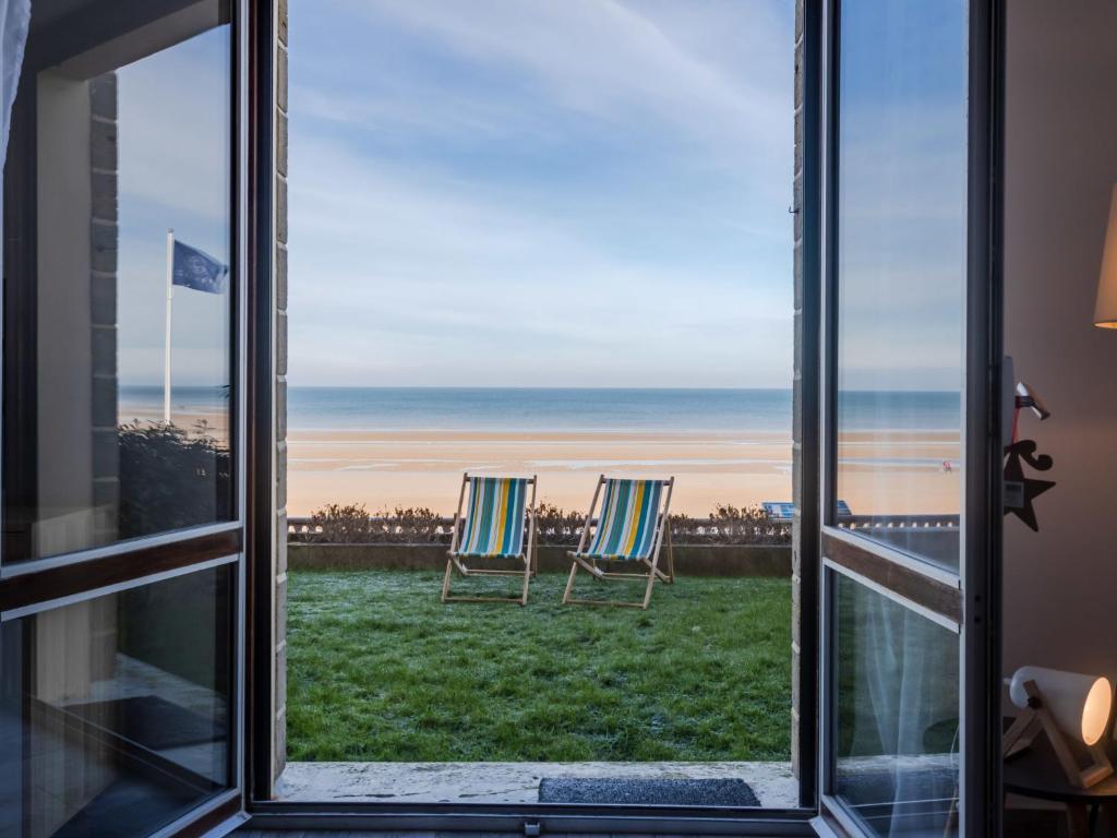 - deux chaises assises sur la pelouse donnant sur une fenêtre donnant sur l'océan dans l'établissement Apartment Les Caravelles-5 by Interhome, à Cabourg