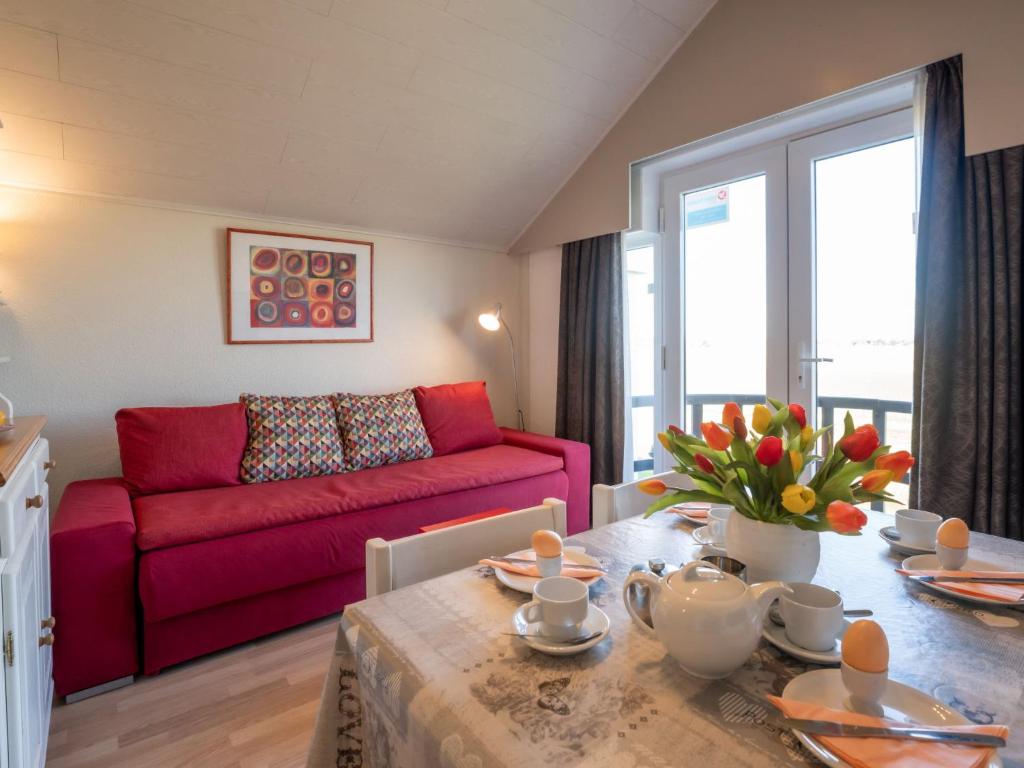 a living room with a red couch and a table at Apartment Dina with parking and shared pool by Interhome in De Haan