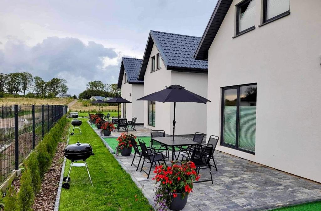 a patio with a table and chairs and an umbrella at Domki Letniskowe Vitamin Sea in Sarbinowo