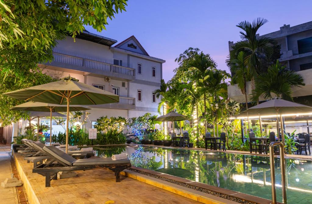 een zwembad met stoelen en parasols naast een gebouw bij Damnak Soksan Hotel in Siem Reap