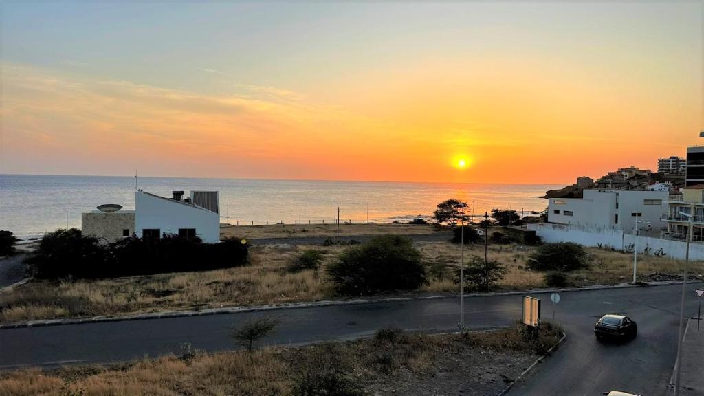 a car driving down a road in front of a sunset at Sunset Apartment in Praia