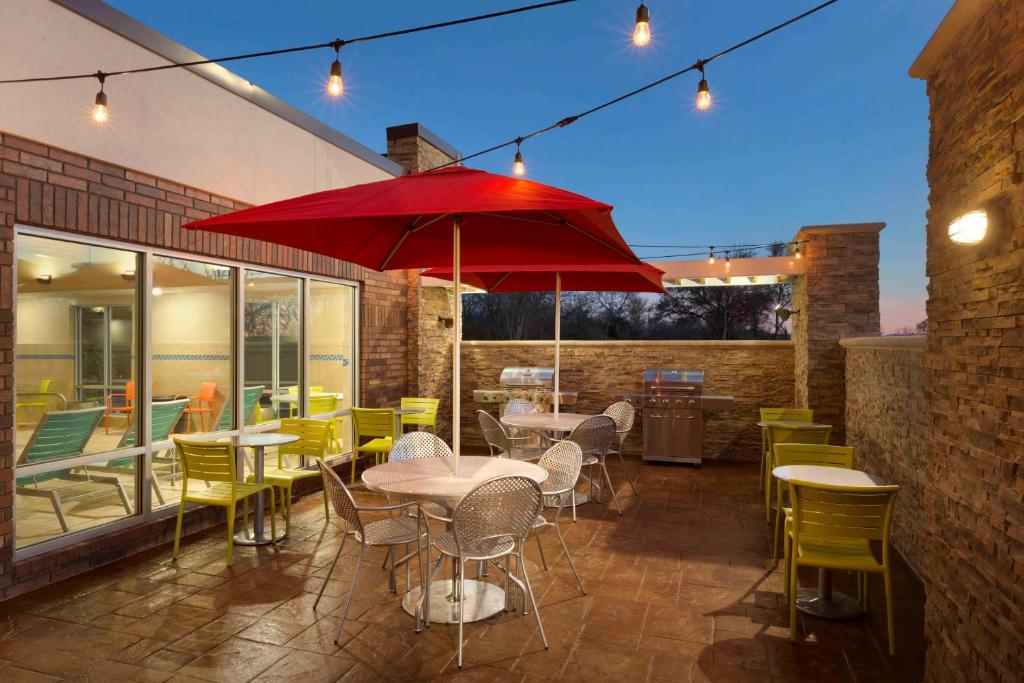 um restaurante com mesas e cadeiras e um guarda-sol vermelho em Home2 Suites by Hilton Fort Smith em Fort Smith