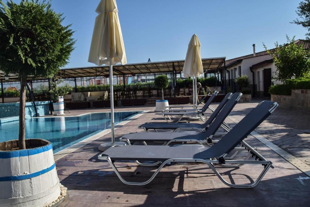 - une rangée de chaises longues et de parasols à côté de la piscine dans l'établissement Sea View Sarafovo, à Sarafovo