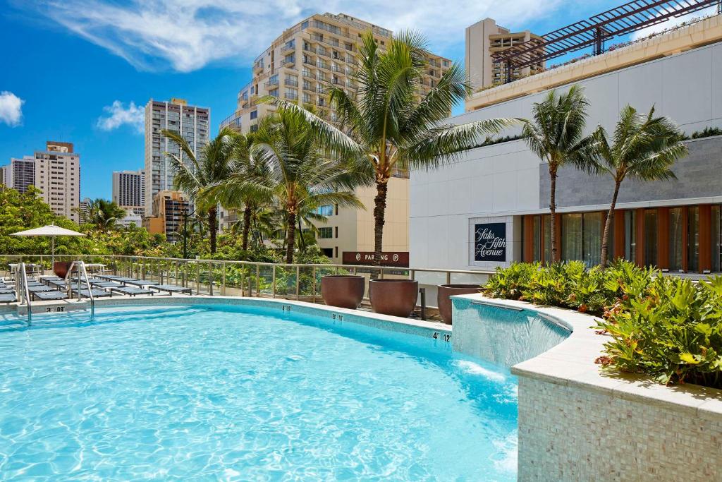 a large swimming pool with palm trees and buildings at Hilton Garden Inn Waikiki Beach in Honolulu