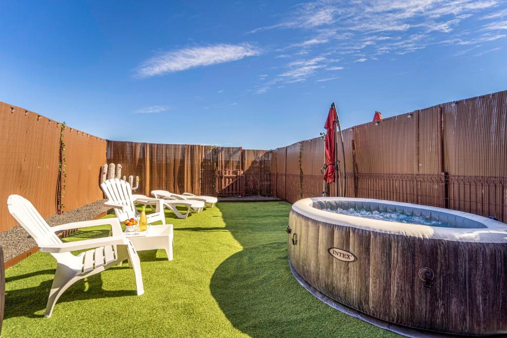 a backyard with a hot tub and chairs and a fence at Villa Colibri Azul in Lajares