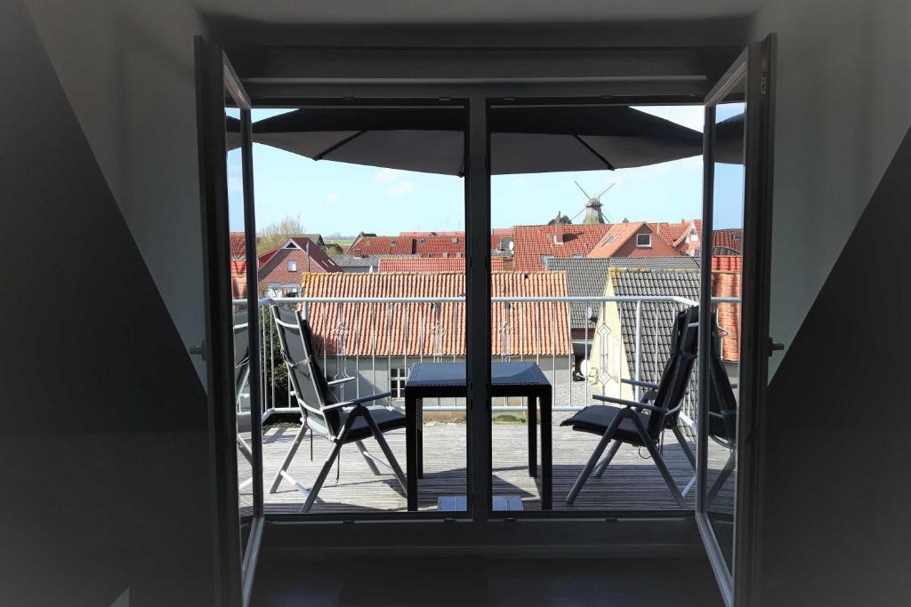un balcon avec une table, des chaises et un parasol dans l'établissement Ferienwohnung Claudia, à Carolinensiel