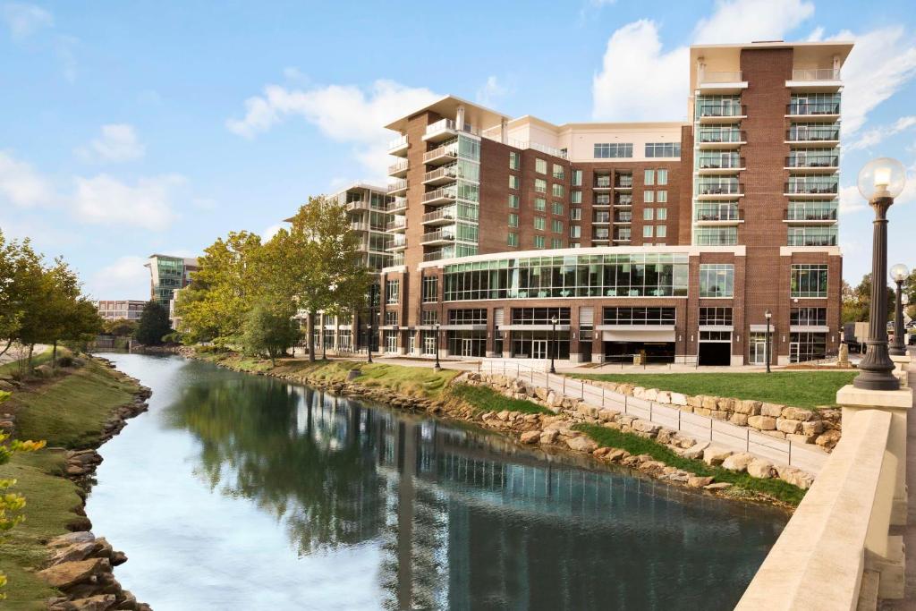 un fiume di fronte a un edificio accanto a un edificio di Embassy Suites by Hilton Greenville Downtown Riverplace a Greenville